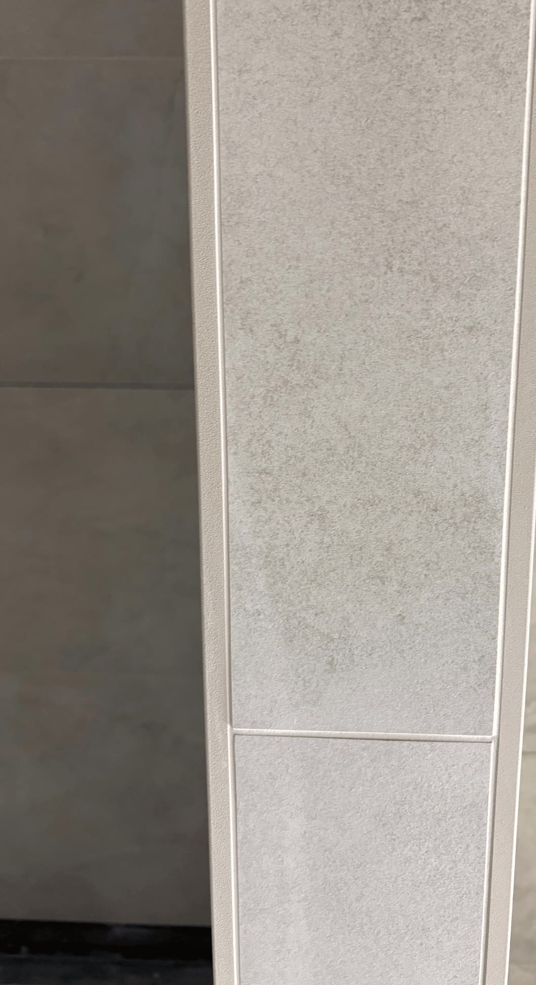 Close-up van een sierstrip tussen wandtegels, met strak afgewerkte voegen.