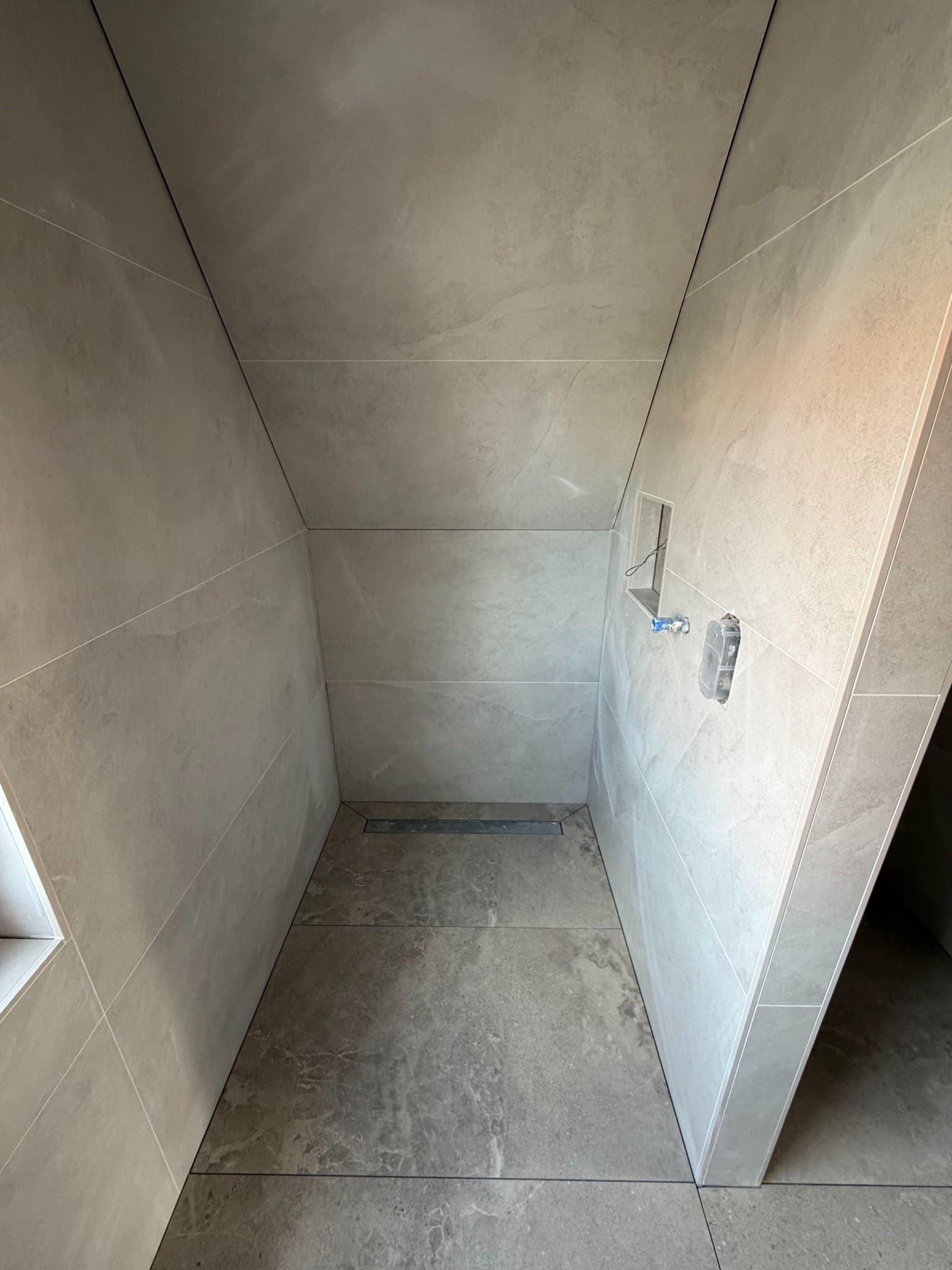 Lichte wand- en vloertegels in de douche van een badkamer in Volendam
