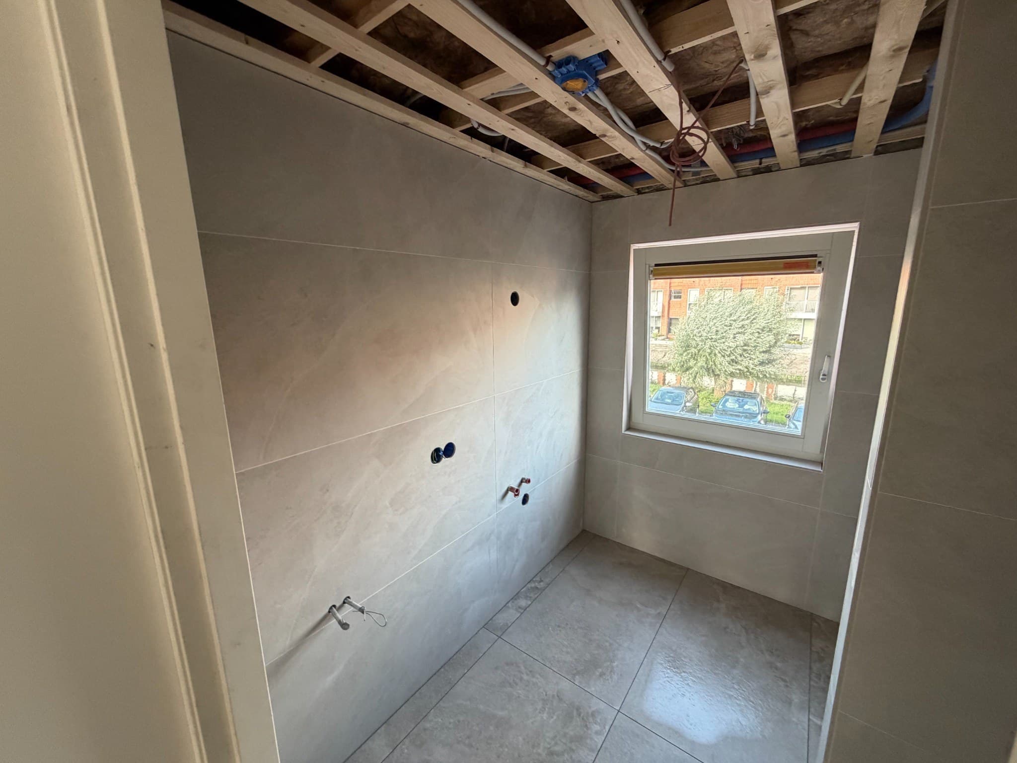 Overzicht van het tegelwerk in een badkamer in Volendam, met het plafond nog in aanbouw